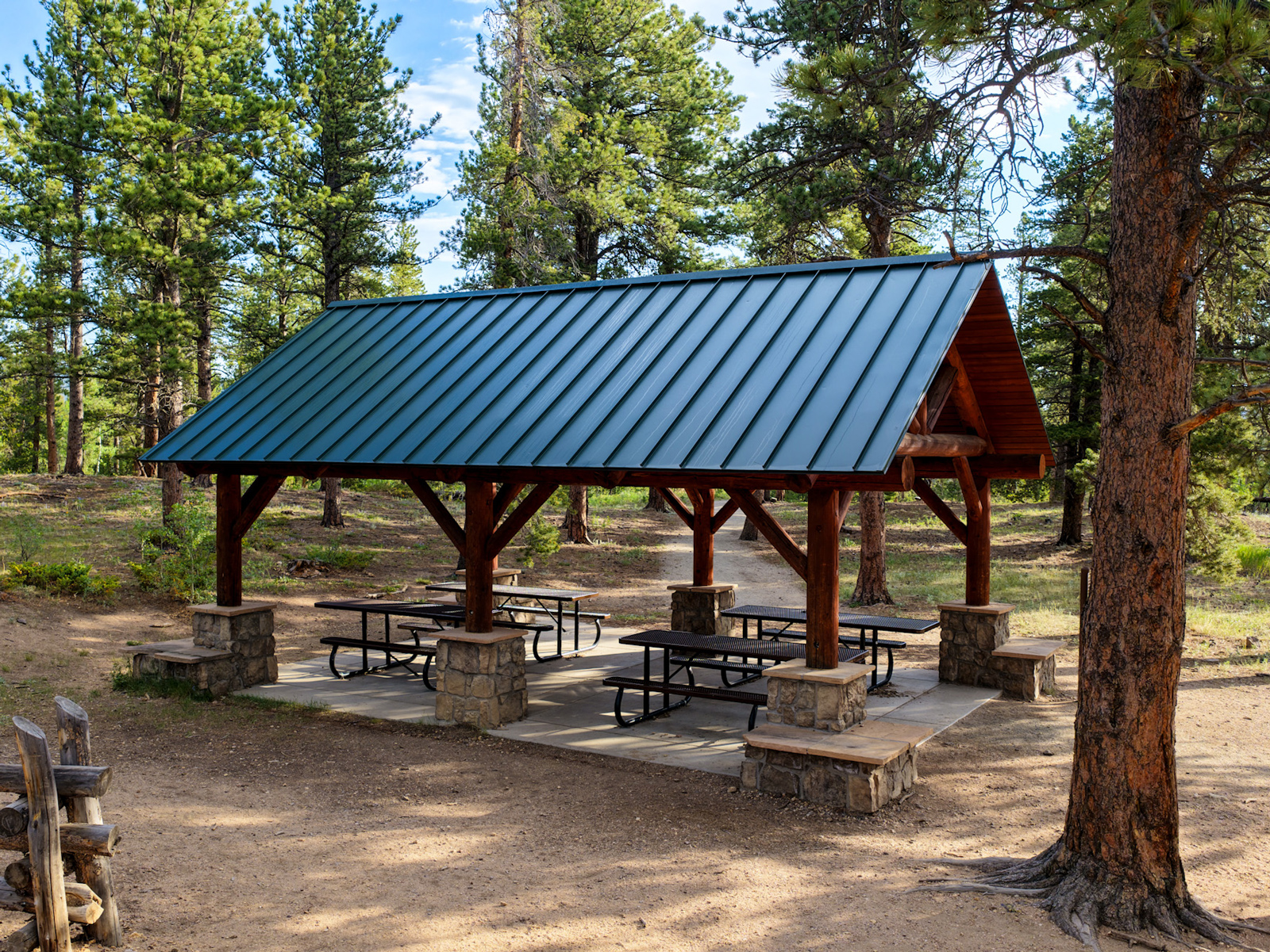 Mud Lake shelter with four picnic tables surrounded by pine trees.
