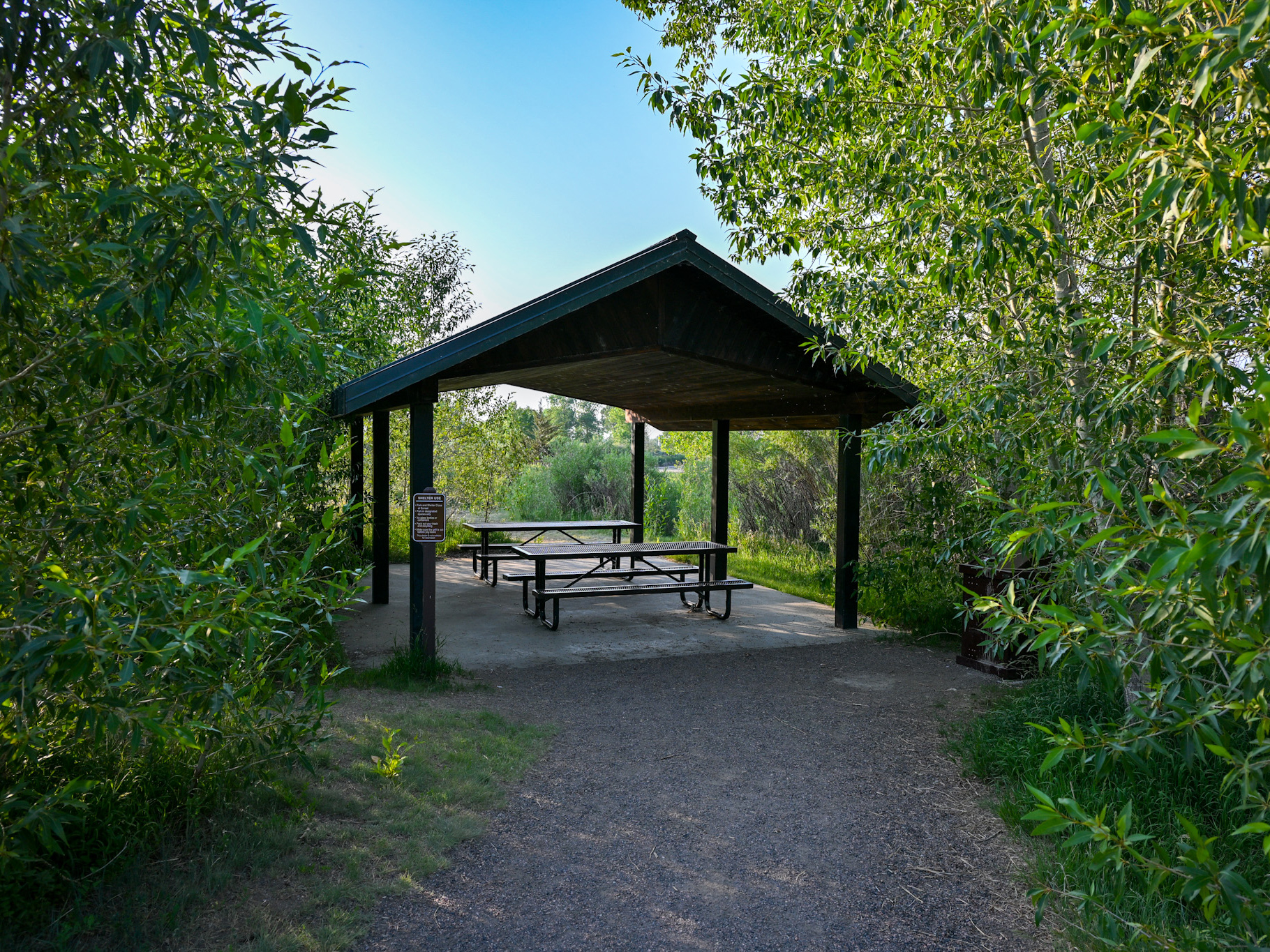 Picnic shelter at Pella Crossing with two picnic tables surrounded by trees.