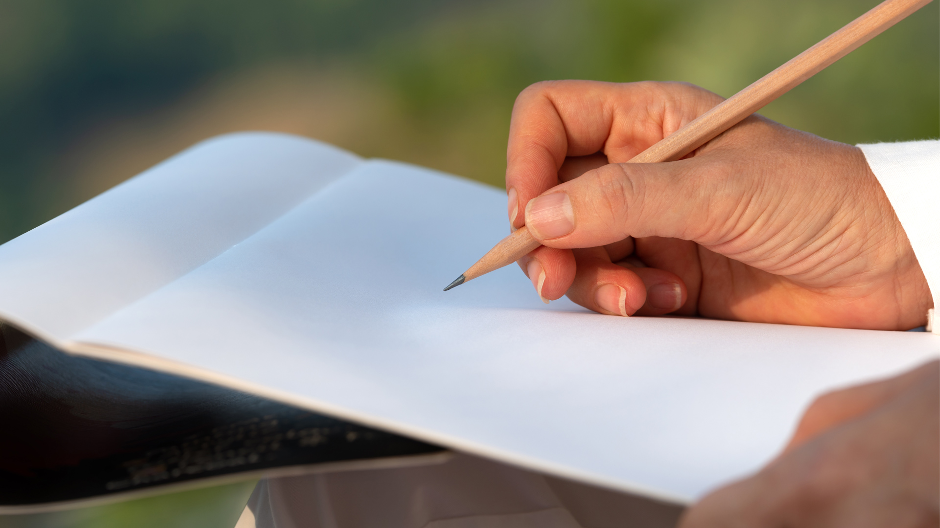 A hand holds a pencil to a sketch pad