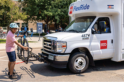 A bicyclist loads a bike onto an RTD bus.