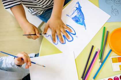 Young children using watercolors and colored pencils.