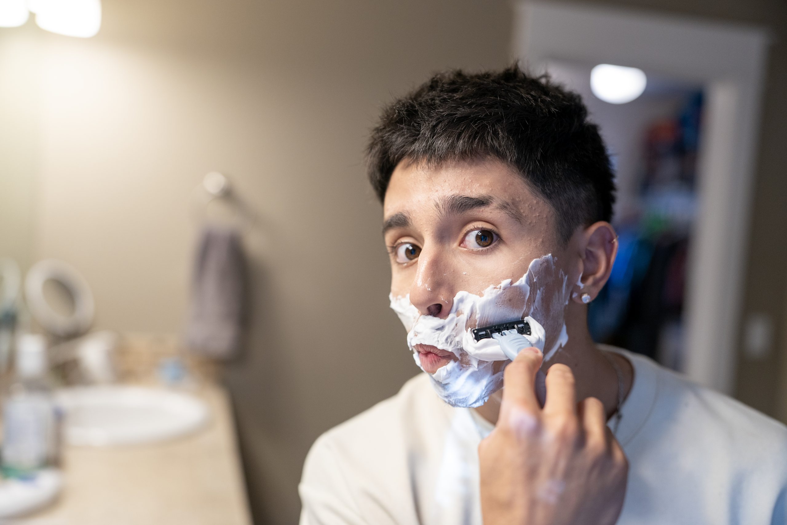 Heat pump hot water heater shaving young man_Living Electric A young man shaves his face