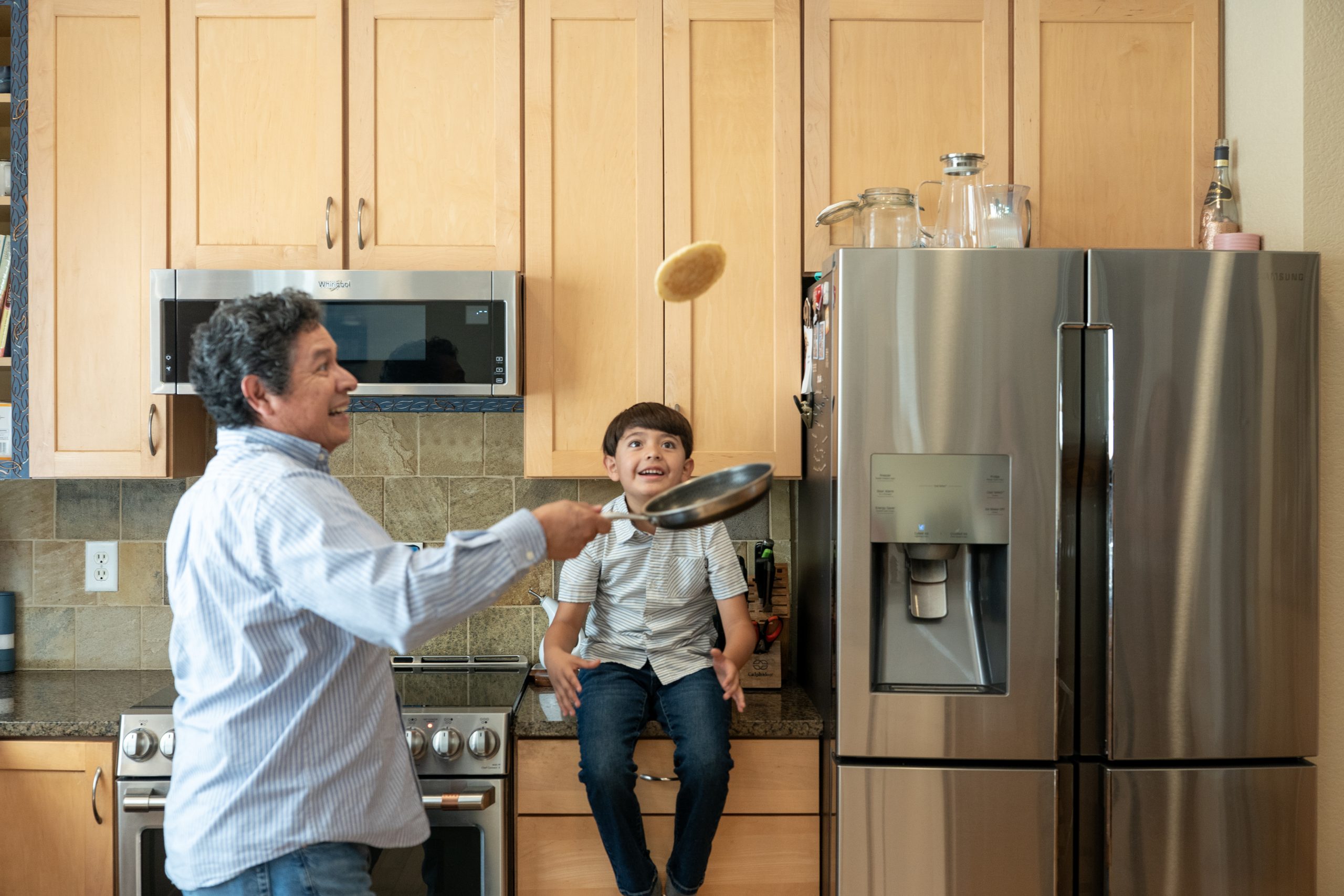 Induction stove Pancake flip_Living Electric A father flips a pancake while his school-age son watches