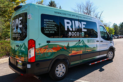 The RideBoCo bus features a prairie and mountain backdrop and a bicycle.